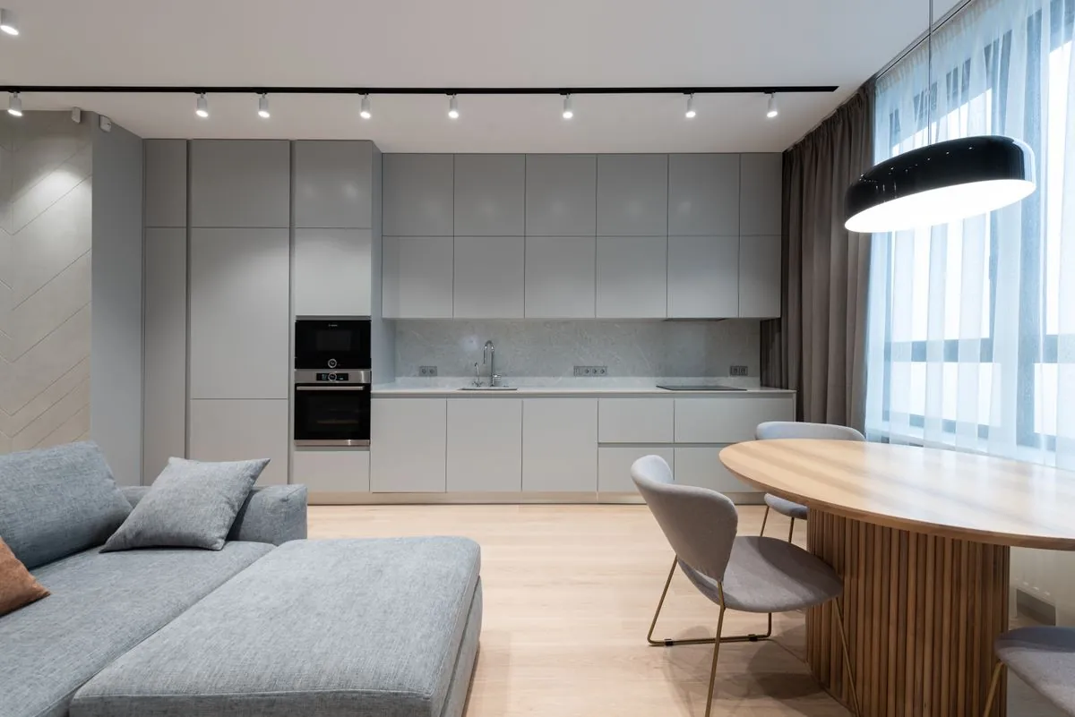 A pale kitchen with an island and wooden stools